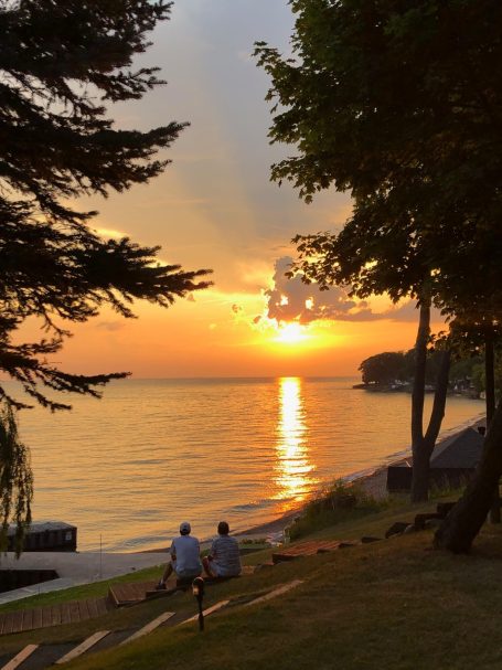 Original Image Provided by My Client Two people sit by the water, watching a sunset over the lake.